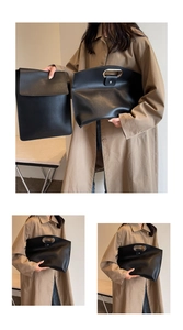 Detail of minimalist black leather briefcase with silver metal handle and embossed logo
