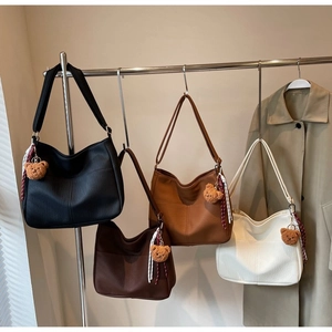 Hobo shoulder bags in four colors with bear charms shown on a display rack