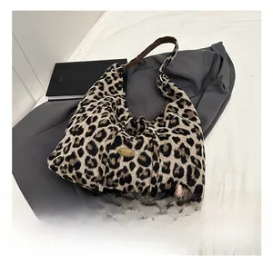 Detail view of leopard print shoulder bag with gold handmade tag on soft faux fur texture