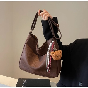 Detail of vintage brown textured leather hobo bag with cute plush bear pendant accessory
