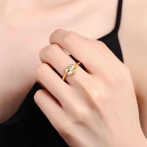 Two-tone hugging hands heart ring in gold and silver finish worn on index finger