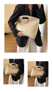 Detail of a beige leather laptop bag featuring a unique hollow metal handle and snap closure