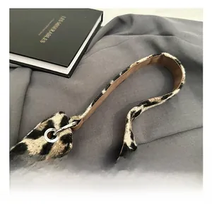 Detail of leopard print faux fur texture and brown smooth handle with silver metal rings