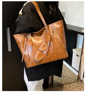 Brown vintage leather tote bag detail with long tassel zippers and stylish side profile