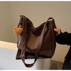 Detailed texture of brown pebble leather tote bag with cute plush bear keychain