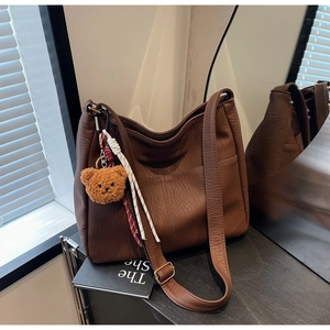 Detail of dark brown pebble leather hobo bag with teddy charm and adjustable strap