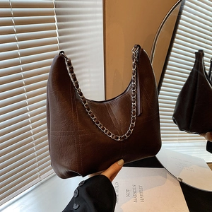 Vintage brown leather hobo bag with chain strap and quilted texture in soft sunlight