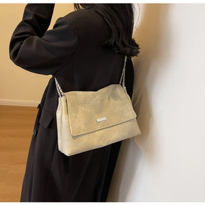 Detailed side view of beige chain shoulder bag showing actual size on a person