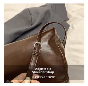 Detail shot of the adjustable shoulder strap with silver buckle on a brown leather tote bag