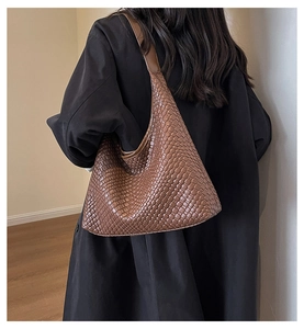 Brown woven leather tote bag showcased on shoulder with minimalist aesthetic design