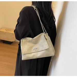 Close-up of minimalist beige tote bag with matte leather texture and silver chain strap