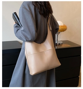 Detailed view of beige hobo tote bag with lychee texture and stitching on a female model