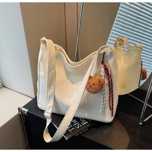 Detail of cream white tote bag featuring wrinkled leather texture and a cute bear charm
