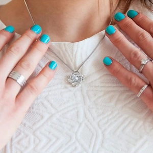 Gros plan d'un collier nœud de cœur argenté avec pendentif zircon et bagues assorties