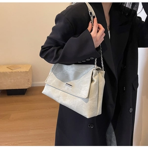 Close-up of a light grey leather tote bag with silver chain strap and metal buckle detail