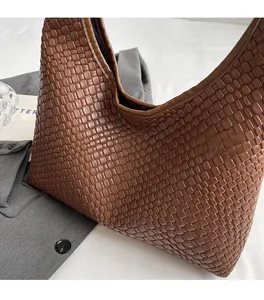 Brown woven tote bag in PU leather displayed on a grey blazer for a stylish look