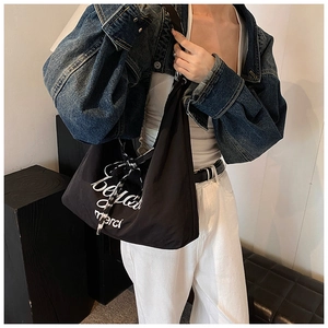 Détail du sac cabas en nylon noir avec lettrage beau et ruban décoratif en soie