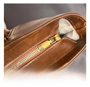 Close-up of premium golden metal zipper and neat stitching on brown leather tote bag