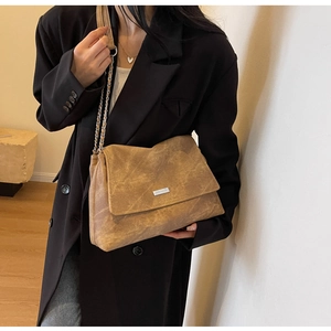 Detail of vintage brown shoulder bag with metallic chain strap and silver logo plaque