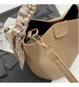 Macro view of light beige bucket bag showing litchi leather and gold-tone hardware