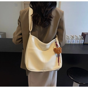 Close-up of beige large capacity tote bag with brown bear charm on shoulder
