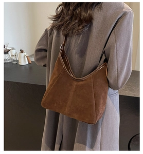 Detail of dark brown suede hobo bag with vertical stitching on a model in a cafe