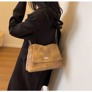 Detail of camel brown crossbody bag with matte texture and silver metal logo plate