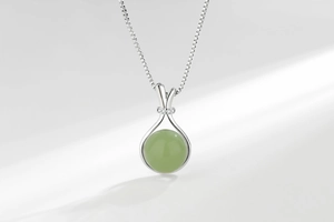 Detailed view of round green jade necklace with silver clasp and sparkling zircon accents