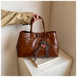 Detailed view of deep brown vintage shoulder bag with metal turn-lock and Binog charm