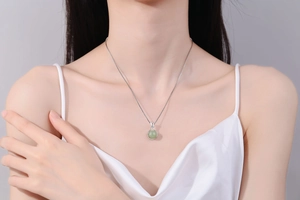 Close-up of minimalist silver lucky pouch necklace with light green jade on a female model