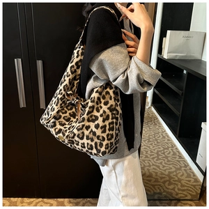 Detail view of large leopard print tote bag with side drawstring bow and metal logo tag