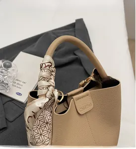 Detail of beige lychee leather bucket bag with silk scarf handle and gold hardware