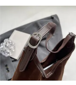 Close-up of brown suede tote bag with adjustable silver buckle and smooth leather trim