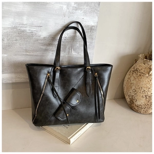 Detail view of vintage dark gray tote bag with leather grain, tassels, and a mini coin purse