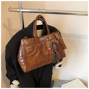 Detail of vintage brown leather handbag with metal buckle and badminton racket pendant