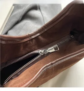 Macro shot of silver metal zipper and smooth suede leather texture on dark brown tote bag
