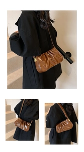 Detail view of brown pleated cloud bag with shiny faux leather texture and gold metal buckle