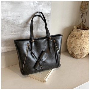 Detail of a large matte leather tote bag in dark grey with metal zipper and hanging charm