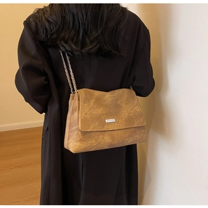 Detail of vintage brown textured leather tote bag with silver chain strap and metal logo