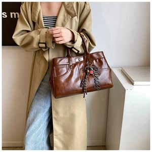 Detail view of retro brown leather tote bag with metallic twist lock and hanging charm