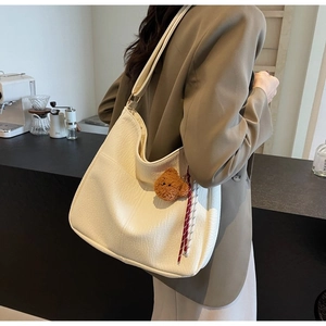 Detail of cream white tote bag with lychee grain texture and cute plush bear charm