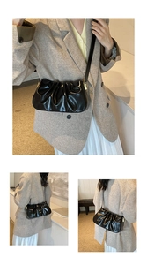 Close-up of black glossy leather pleated cloud bag with elegant shoulder strap detail