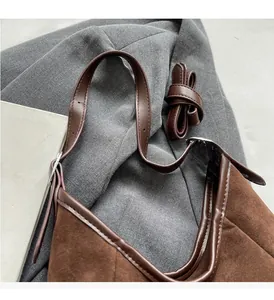 Detail view of brown suede tote bag featuring reinforced handle and detachable shoulder strap