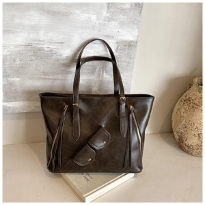 Detailed view of dark brown tote bag with metal zippers and elegant gold-tone hardware