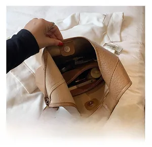 Detail view of large brown pebble leather tote bag showing internal zipper pocket and storage
