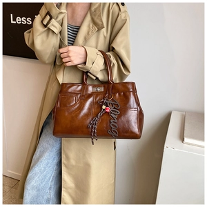 Close-up of vintage brown tote bag featuring metallic twist lock and decorative charm