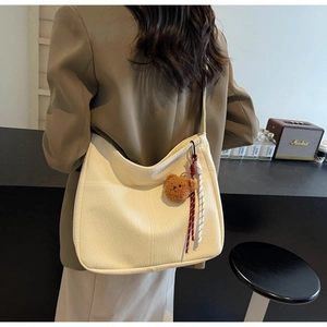 Close-up of off-white lychee grain tote bag with bear charm and braided rope detail