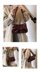 Detail showing deep red pleated cloud bag with glossy patent leather finish