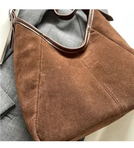 Detail of dark brown suede tote bag with reinforced leather seams and stitching