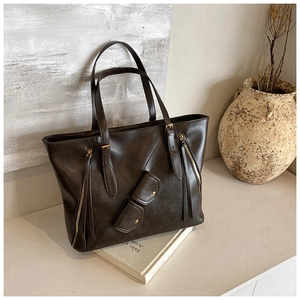 Detail of vintage coffee brown tote bag with leather tassels and brass buckles on a book